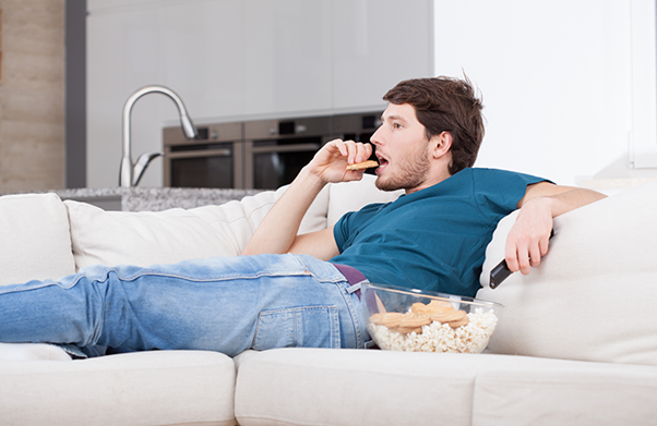 Mann, der auf einem Sofa sitzend isst